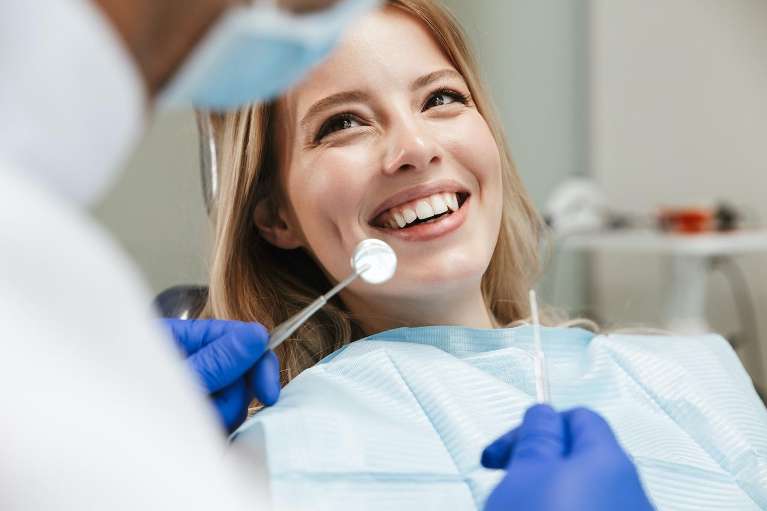 Woman smiling at dentist in Topeka after oral surgery.